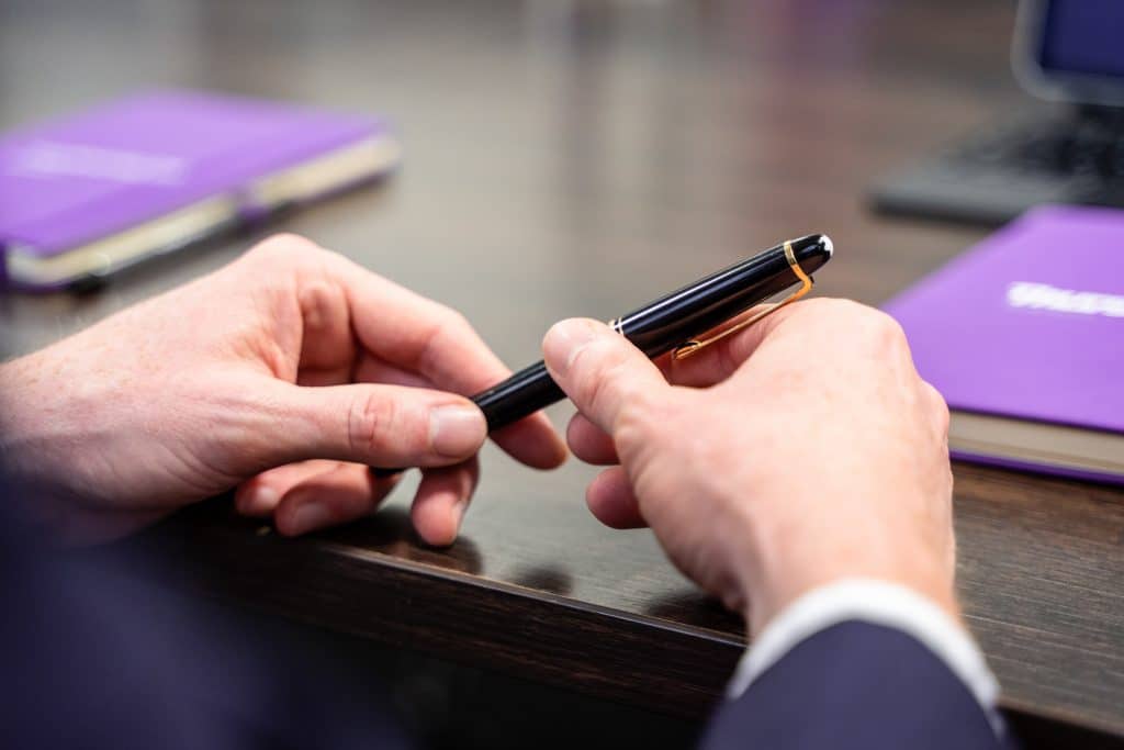 Employment Law - Man sat holding pen against table